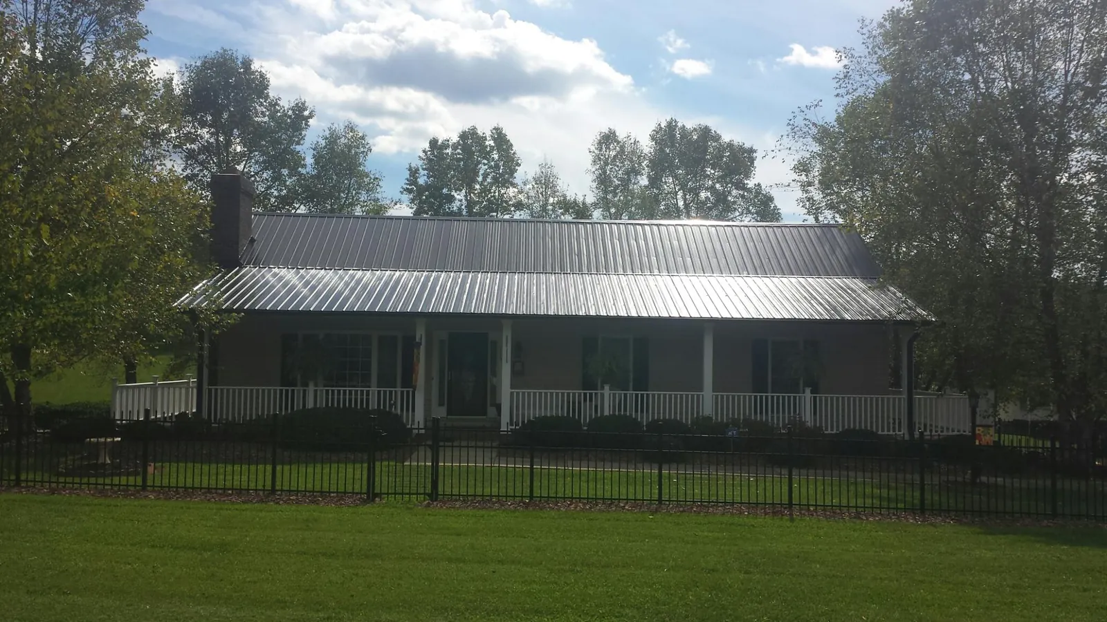 Gray metal roof on a brick ranch with a full width front porch — Gutter Guard Installation work by our crew in Orange City