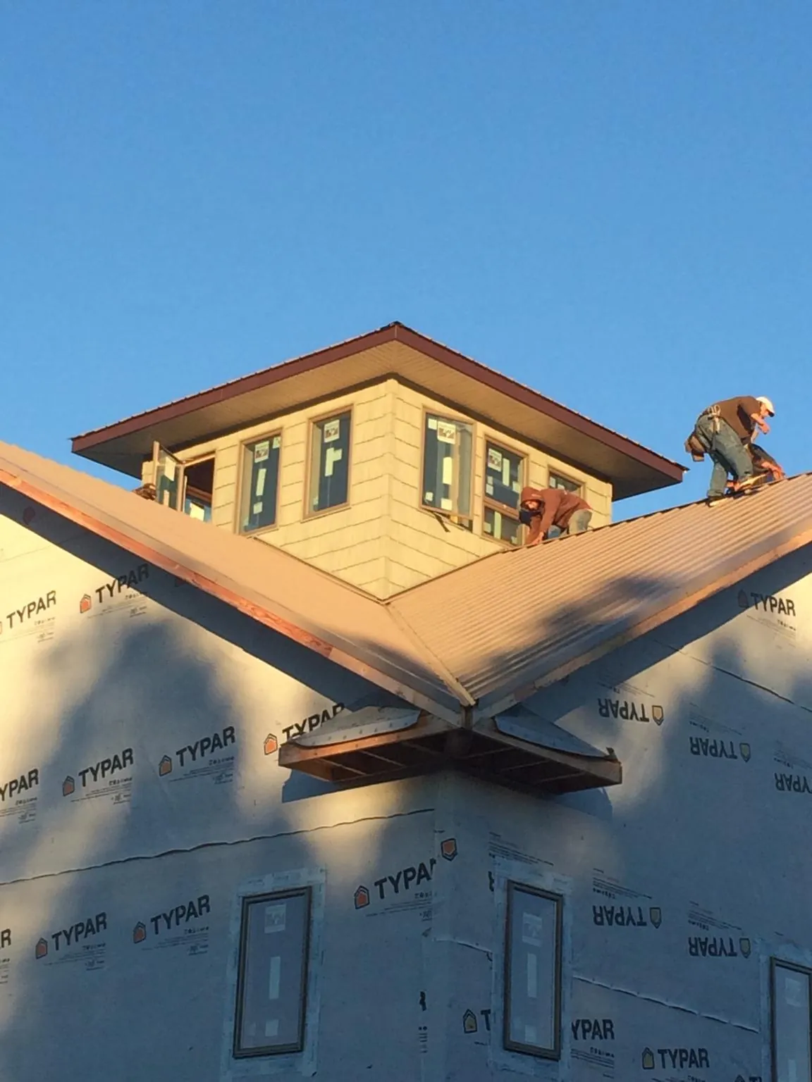 Roofers working around a rooftop cupola on a new metal roof at sunset — Roof Waterproofing in Orange City by Roofing Brothers